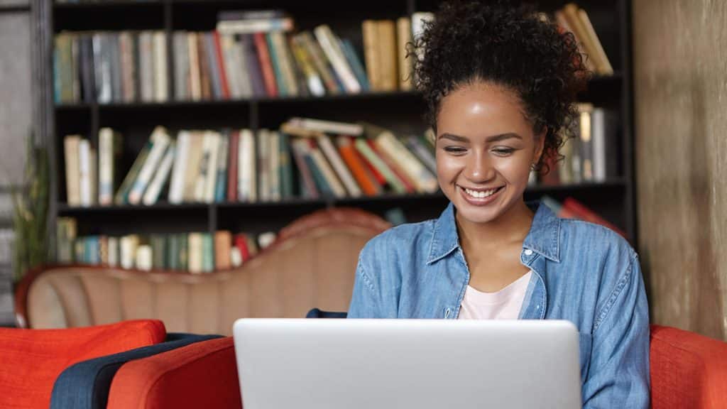 woman studying for her online degree on laptop in book lined room