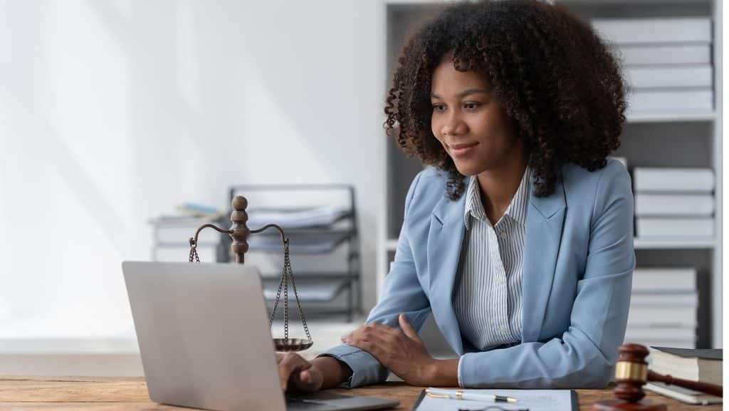 legal student works on laptop next to the scales of justice and gavel