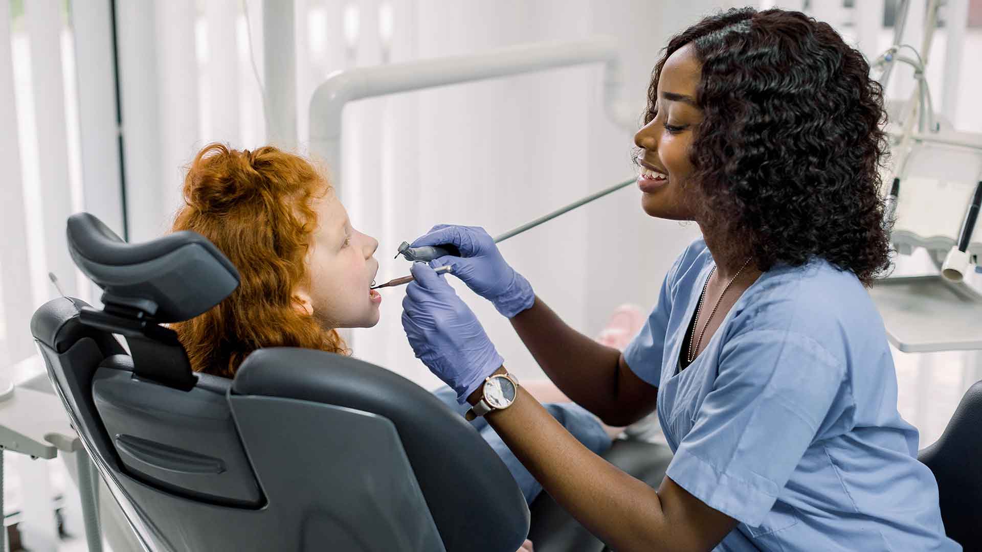 dental assistant cleans young girls teeth