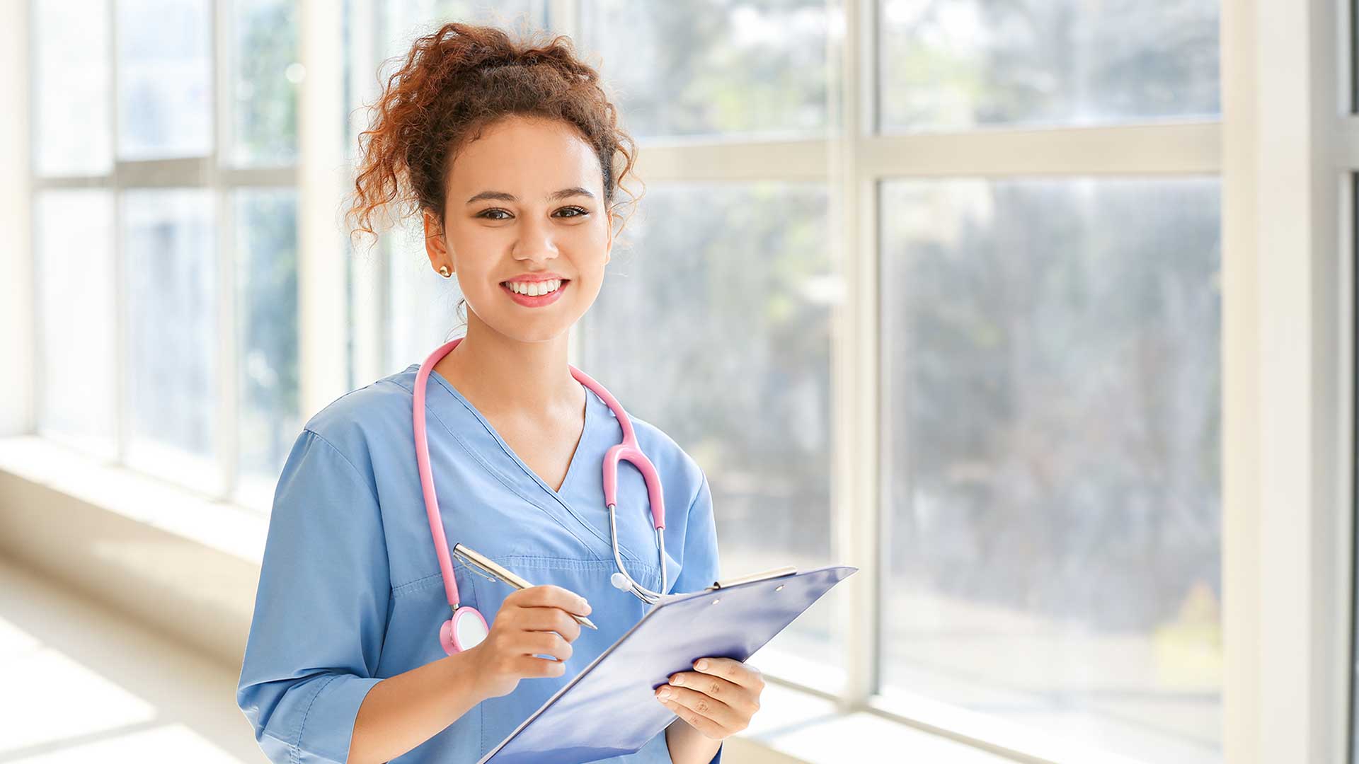 medical assistant near sunny window holding patient chart