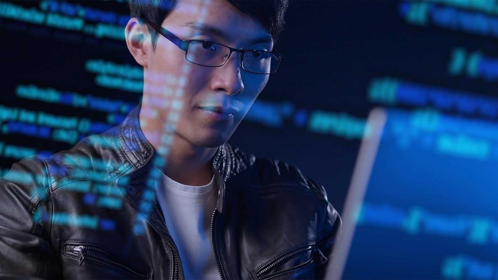 computer scientist works on code on desktop as data is superimposed on image
